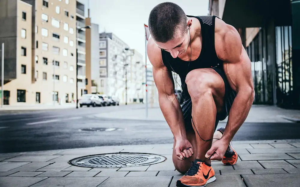 fitness homme laçant ses chaussures avant un entrainement sportif