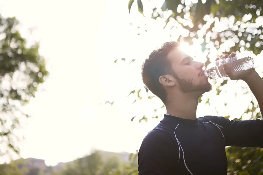 homme s'hydratant après effort physique d'une course de running