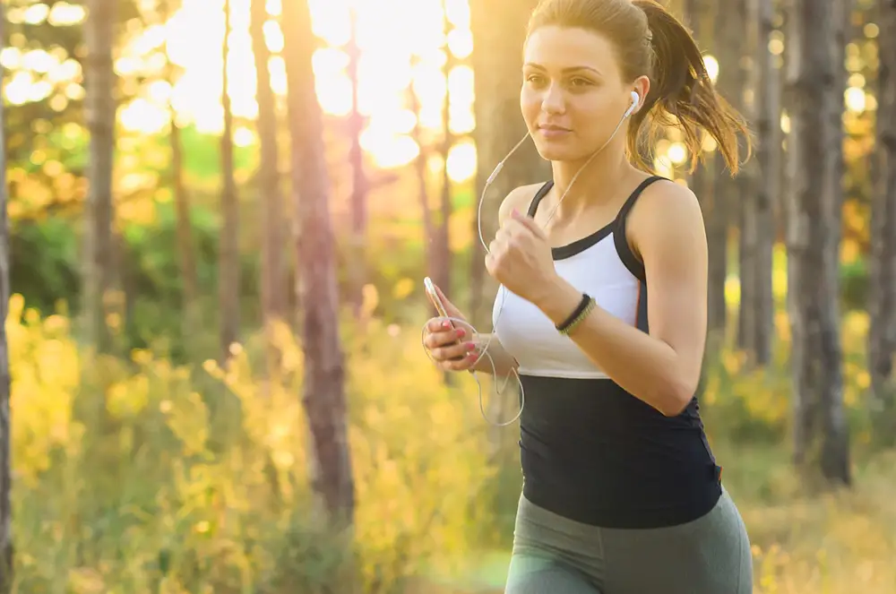 jeune femme courant en nature avec écouteurs dans les oreilles